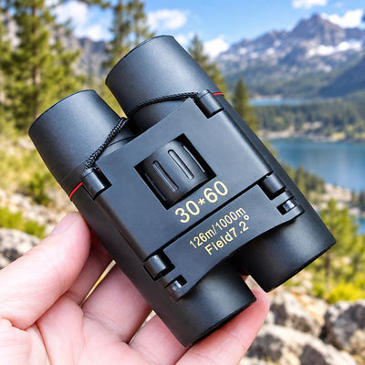 Jumelles TrekPocket compactes en main devant paysage montagneux naturel aventure