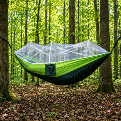 Hamac moustiquaire TrekShield suspendue vert et noir installé entre des arbres.