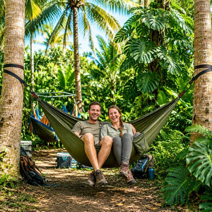 Hamac pour 2 personnes avec un couple assis dans une forêt tropicale entourée de palmiers et de végétation luxuriante.